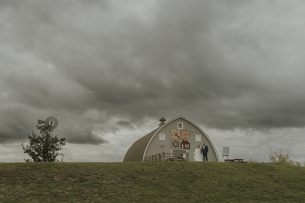 a couple standing in front of a barn under a cloudy sky