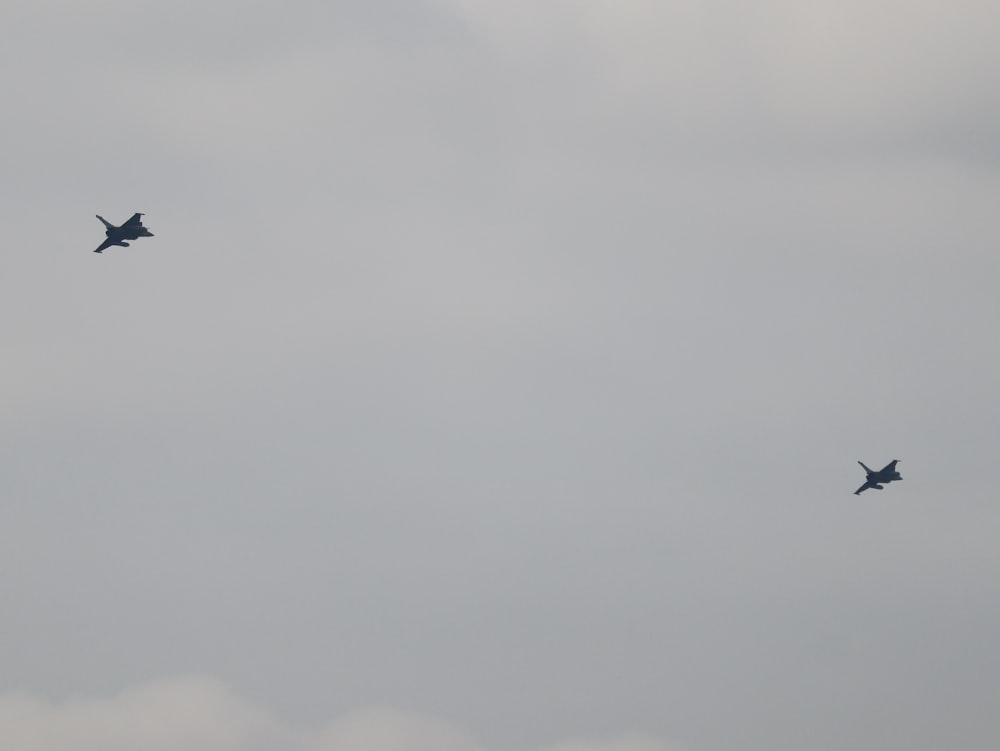 two fighter jets flying through a cloudy sky