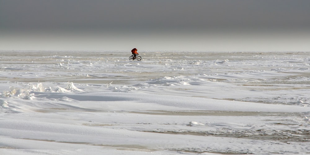 a man riding a bike through a snow covered field