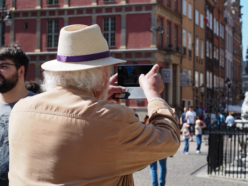 a man in a hat taking a picture with a cell phone