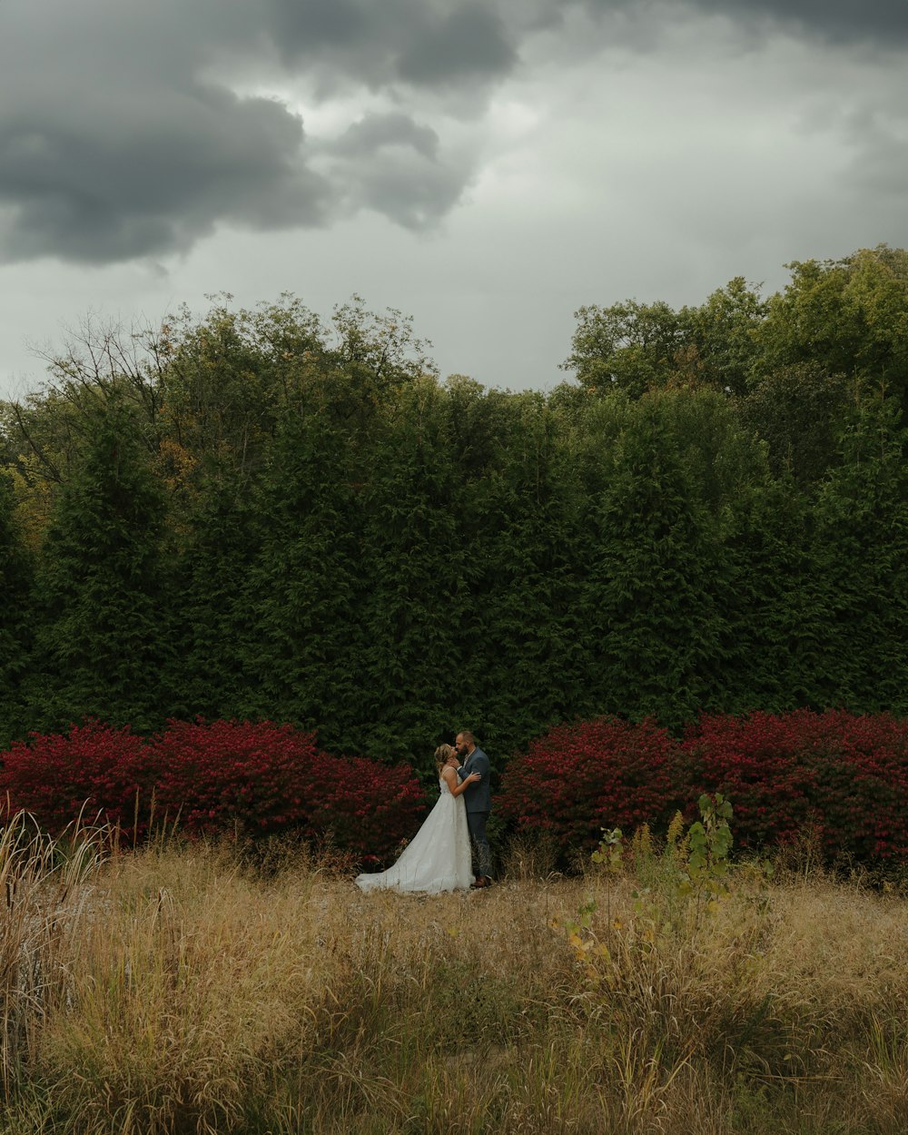 a bride and groom standing in a field