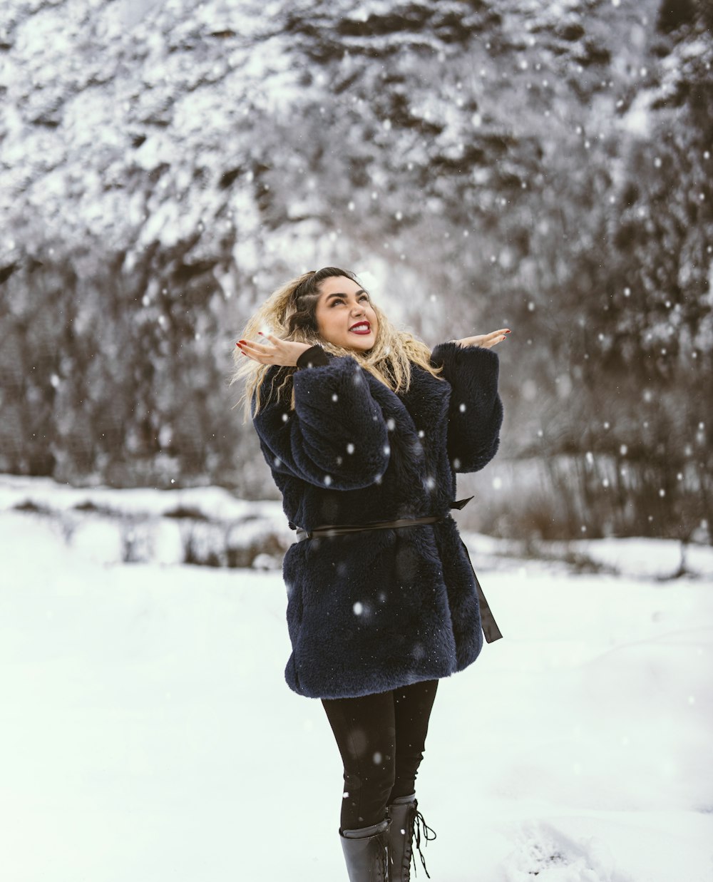 a woman standing in the snow with her arms outstretched