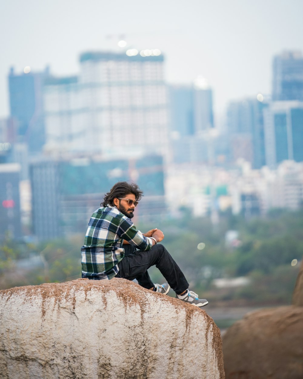 a man sitting on top of a rock next to a city