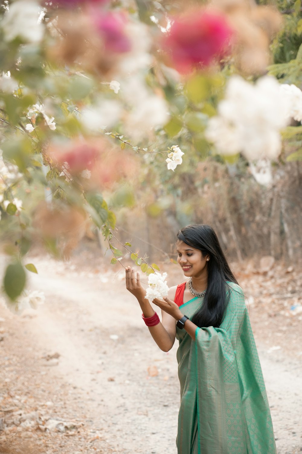 a woman in a green sari holding flowers