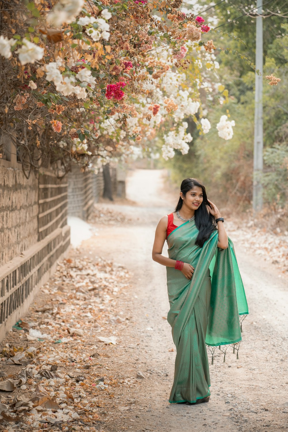 a woman in a green sari standing on a dirt road