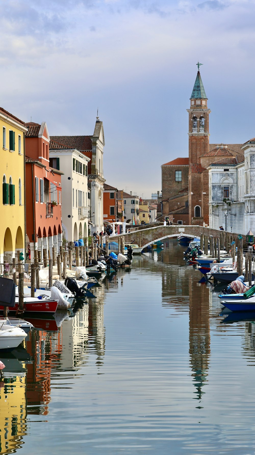 a canal with many boats in it and a clock tower in the background