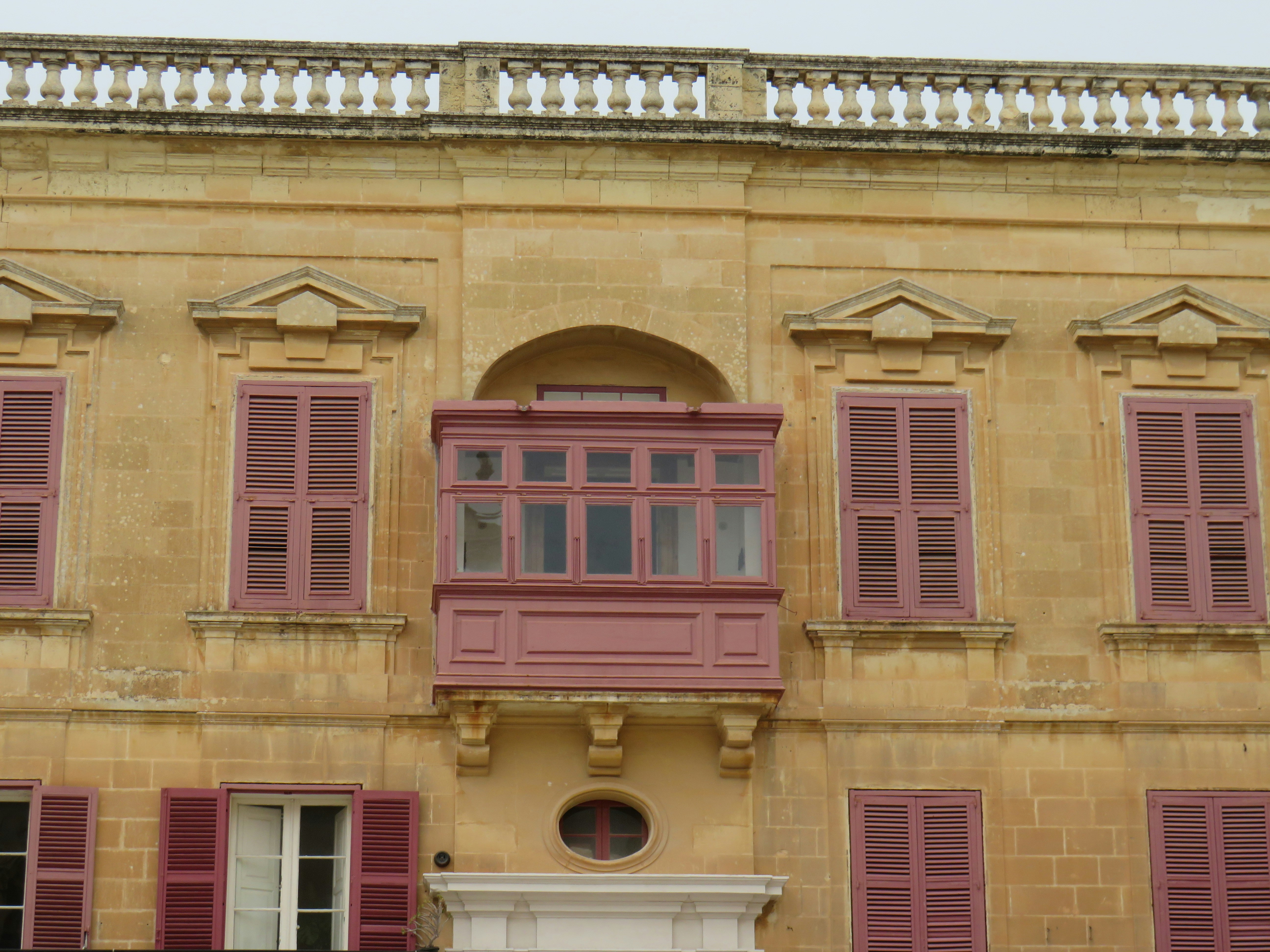 a tall building with red shutters and a clock