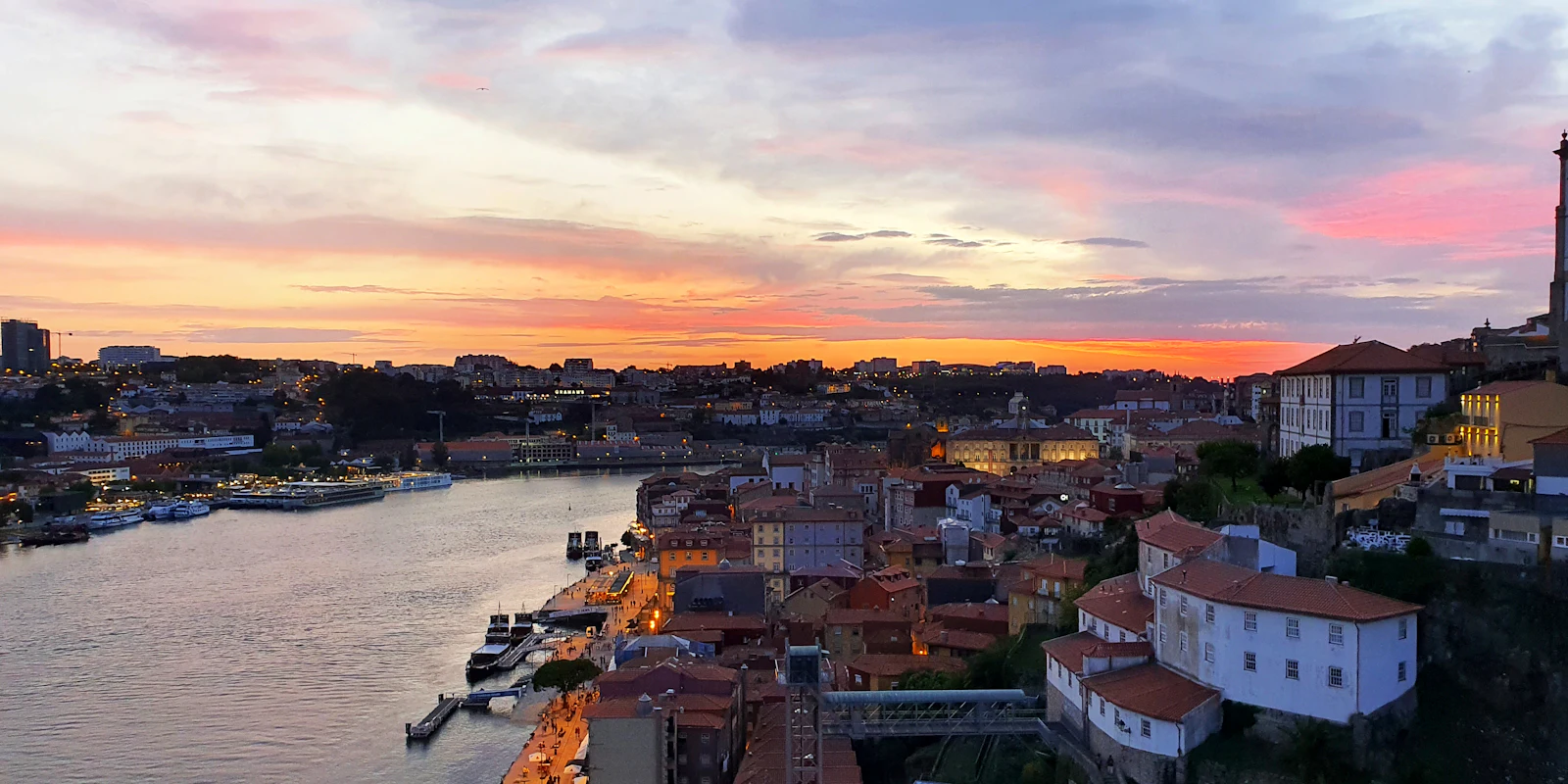 Porto's riverside houses and the Douro River under a pink and orange sunset, a city easy to explore with a Portugal eSIM