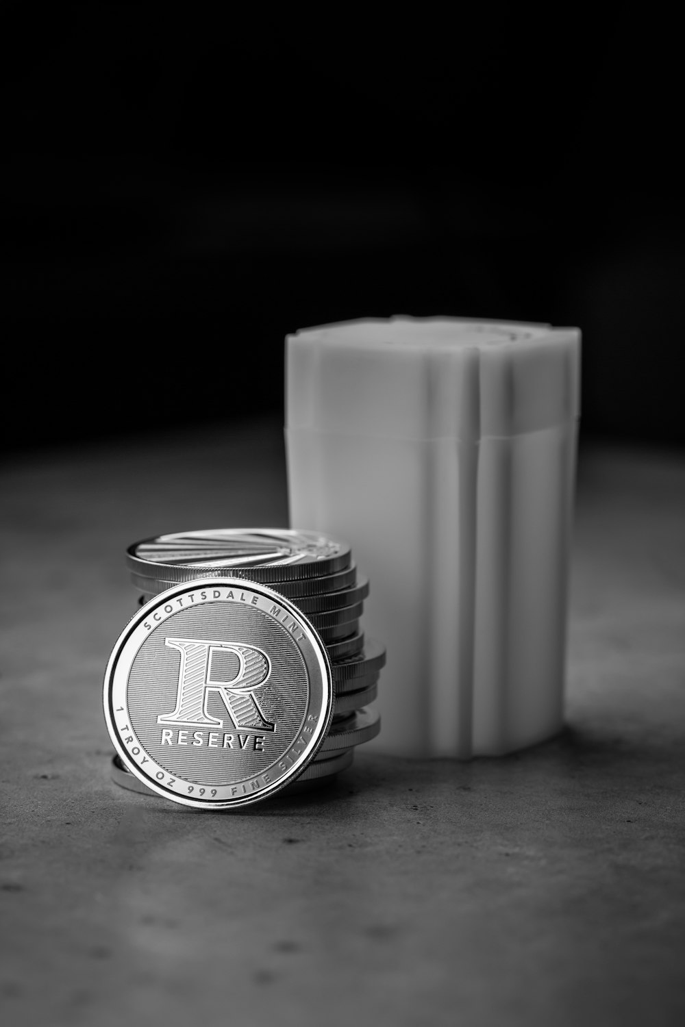 a stack of silver coins sitting next to a white container