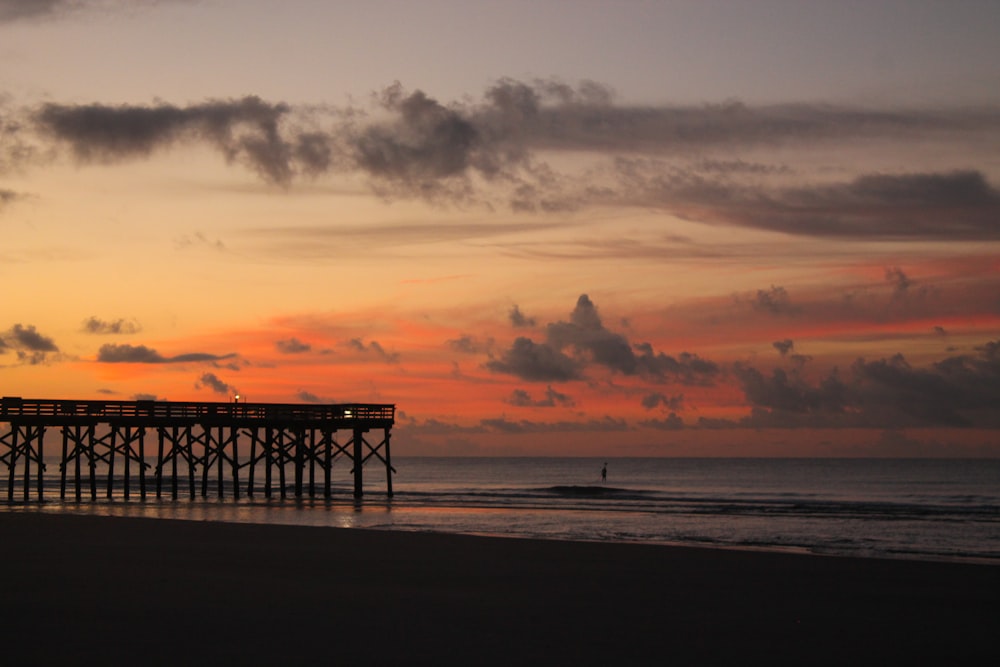 a pier at the beach during a sunset