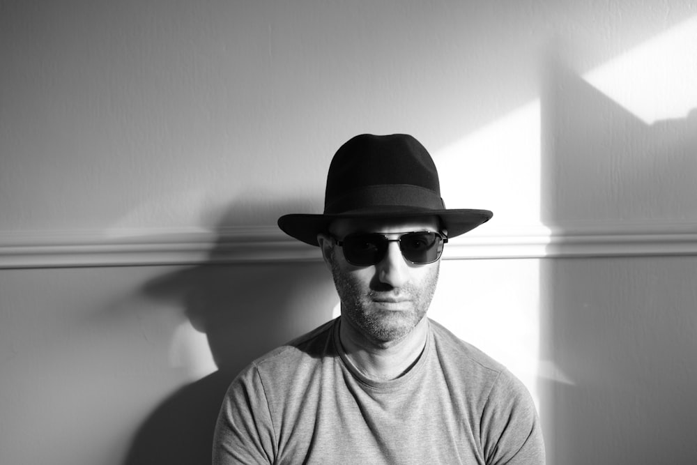a man wearing a hat and sunglasses poses for a picture