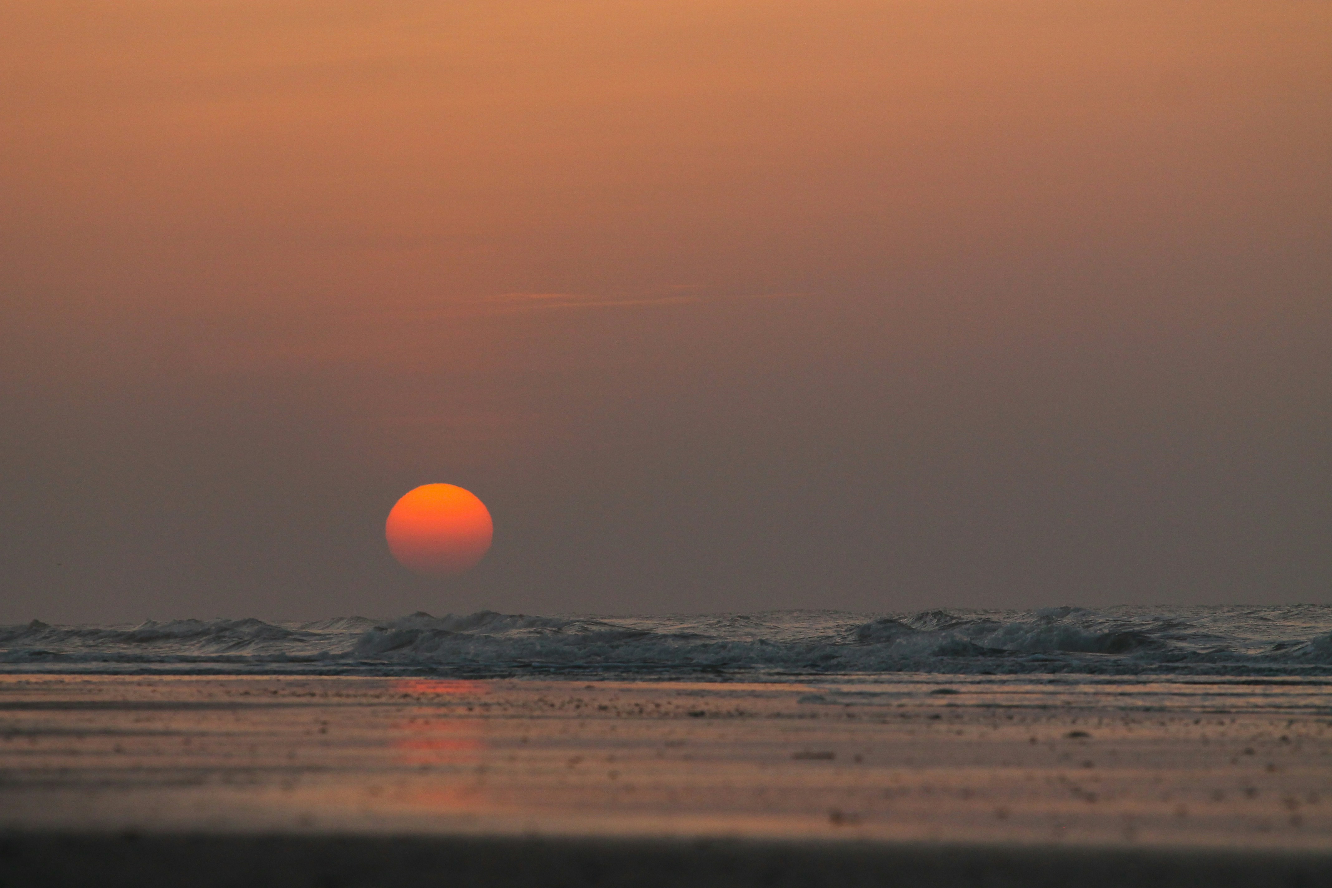 the sun is setting over the ocean on the beach