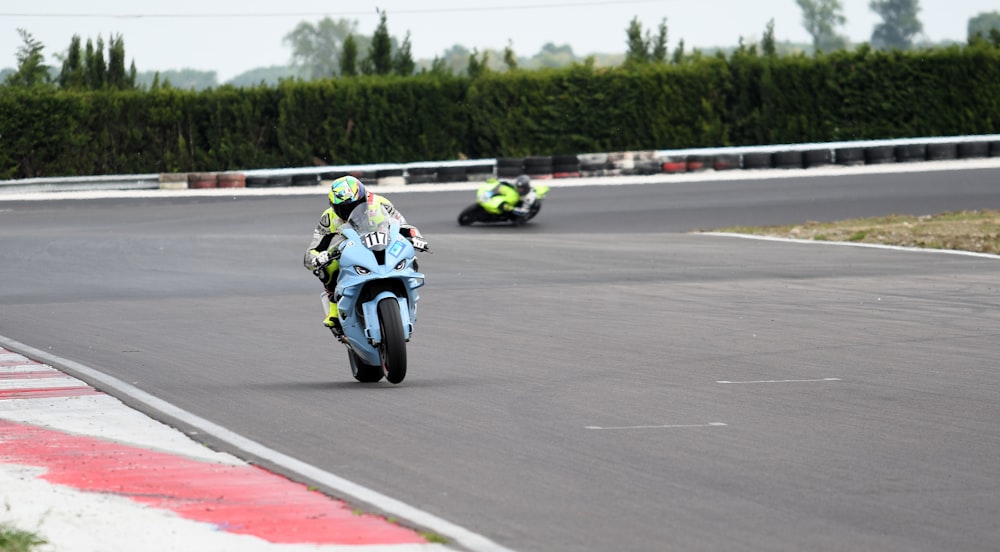 two people riding motorcycles on a race track