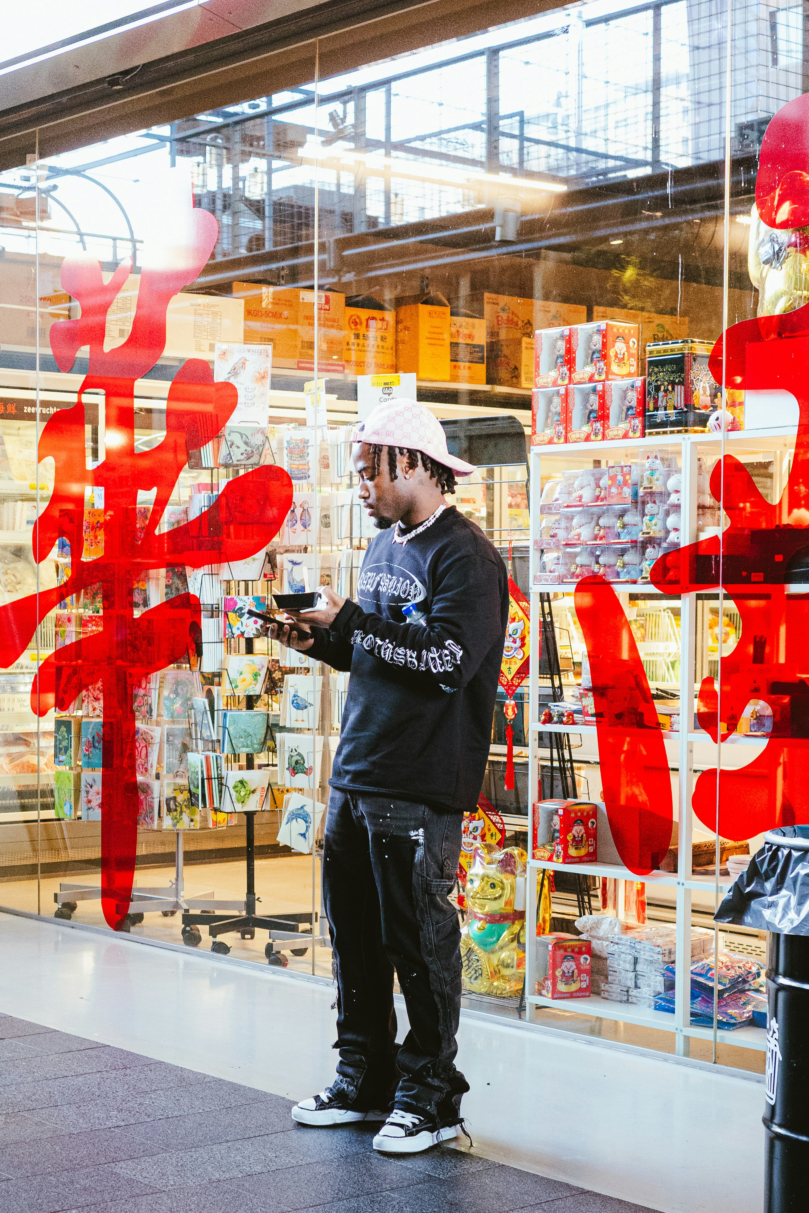A man checks his phone in front of a store.