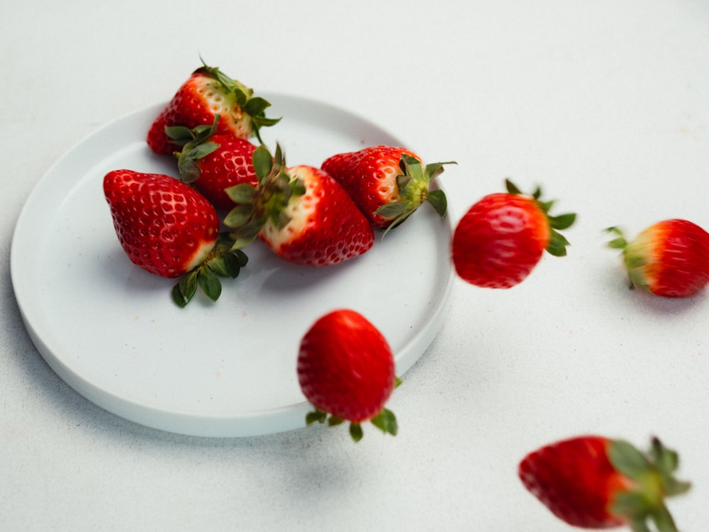 a white plate topped with strawberries on top of a table