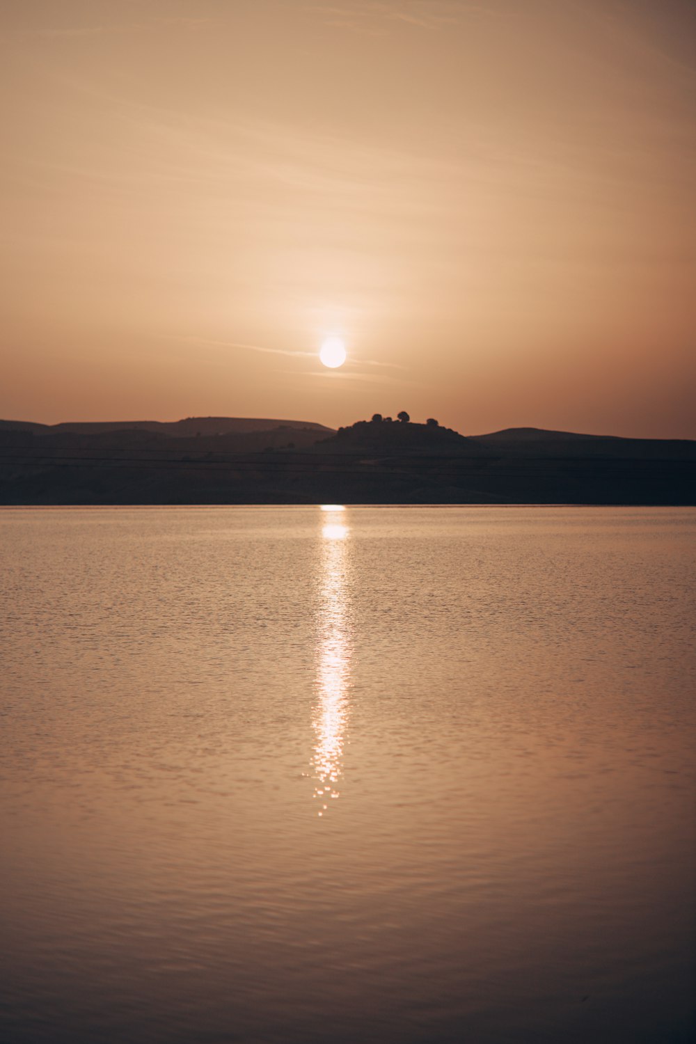 a large body of water with a sunset in the background