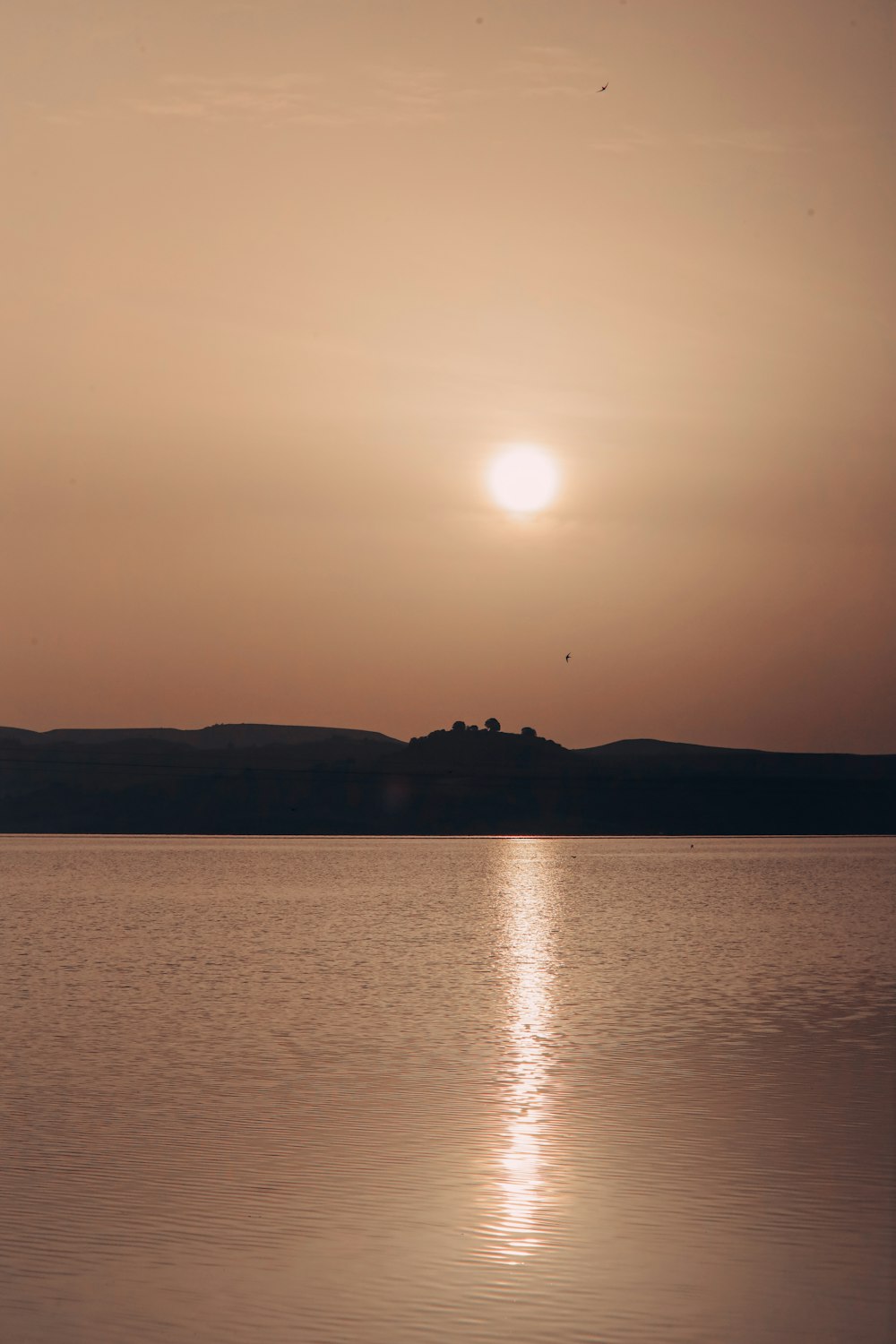 a large body of water with a sunset in the background