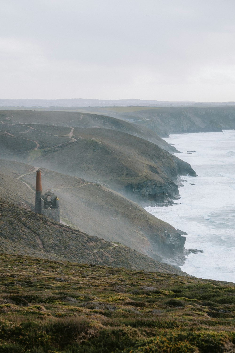 a foggy view of the ocean with a lighthouse in the foreground