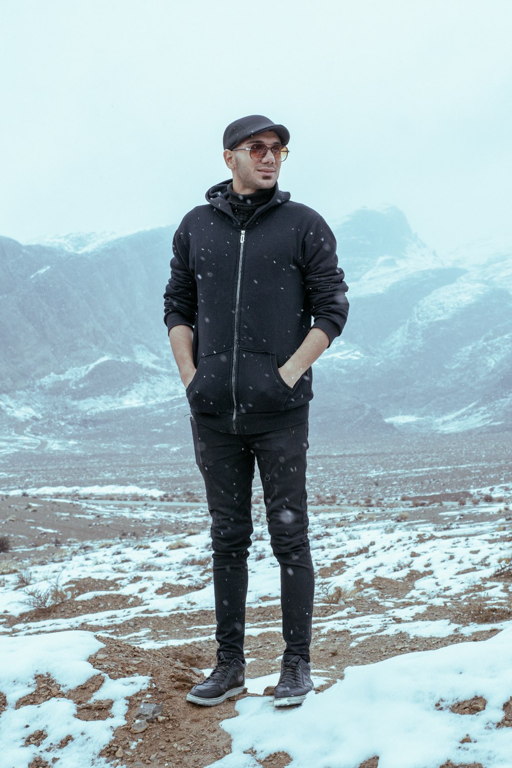 a man standing in the snow wearing a black jacket