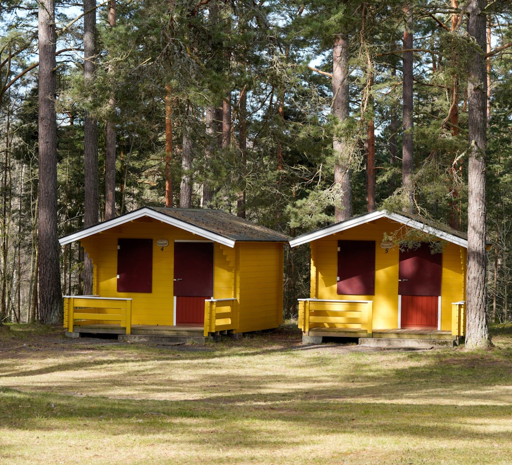 a couple of yellow buildings sitting in the middle of a forest