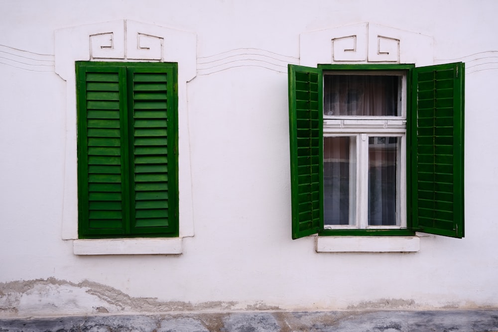 a white building with green shutters and a window