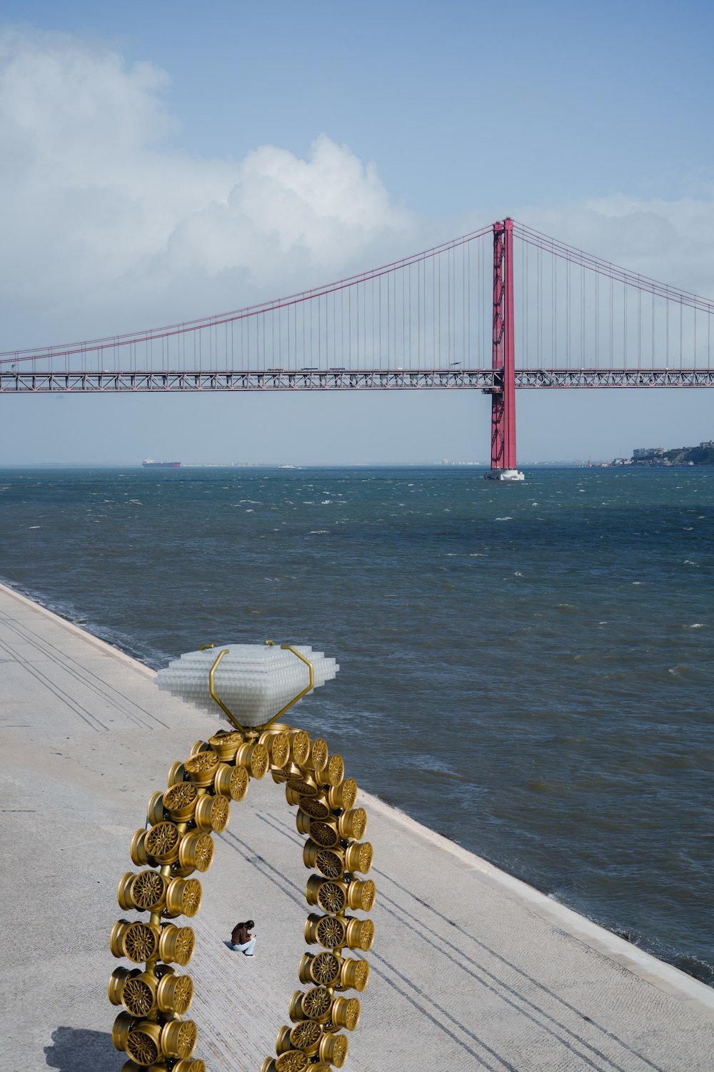 a statue of a life - sized lifeguard on a beach near a bridge