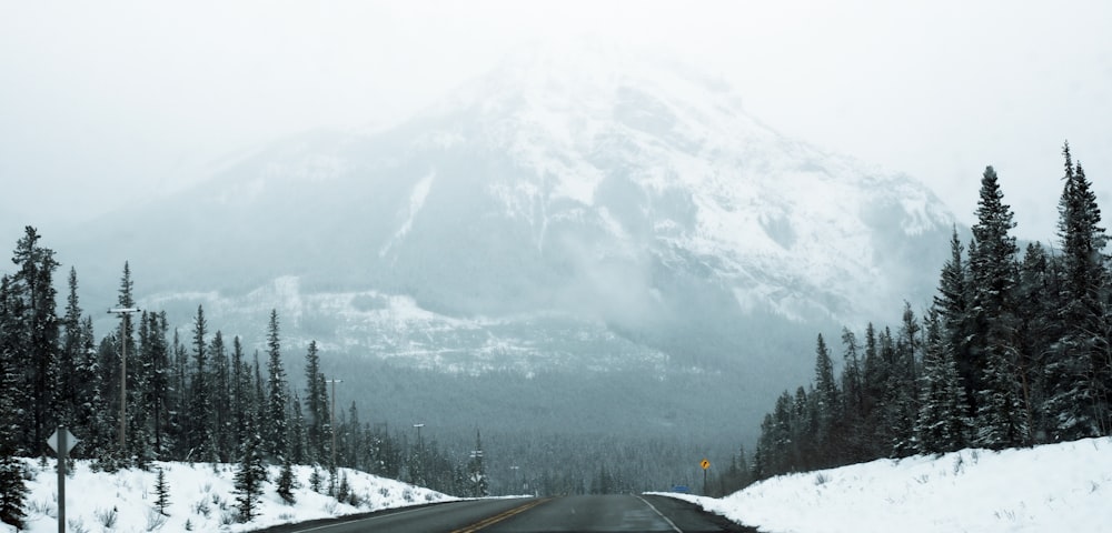 a snowy road with a mountain in the background