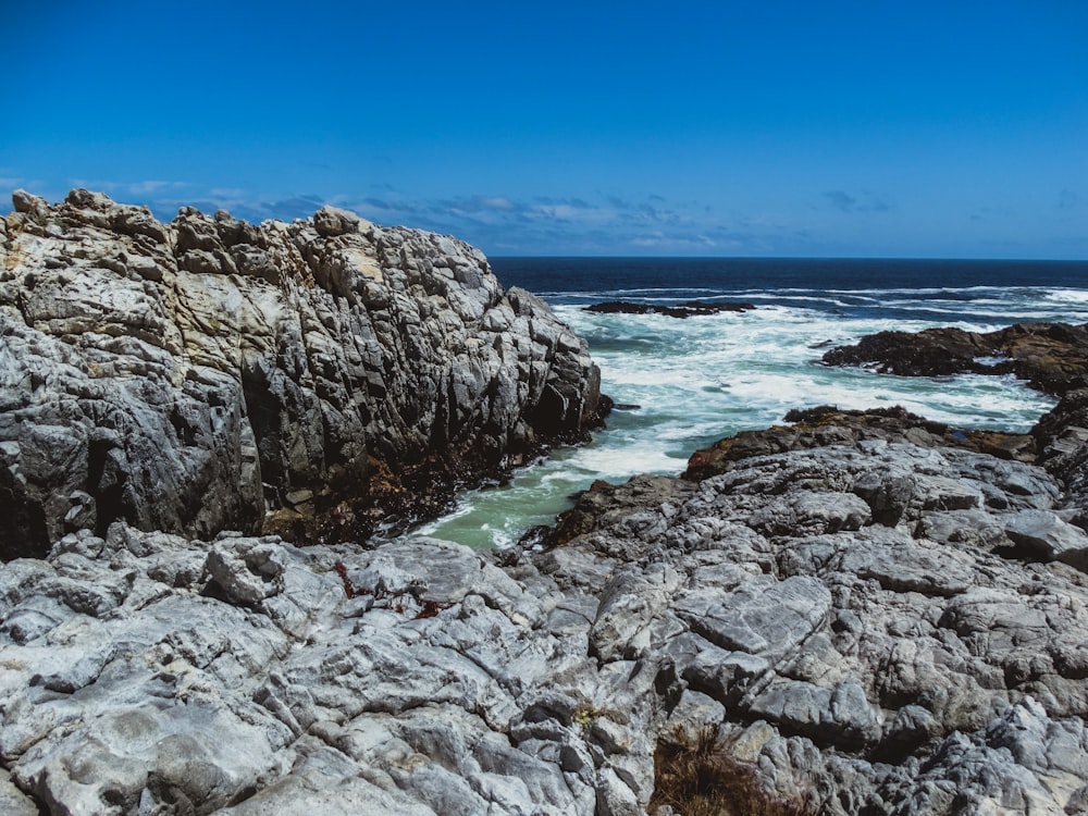 a rocky shore with a body of water in the distance