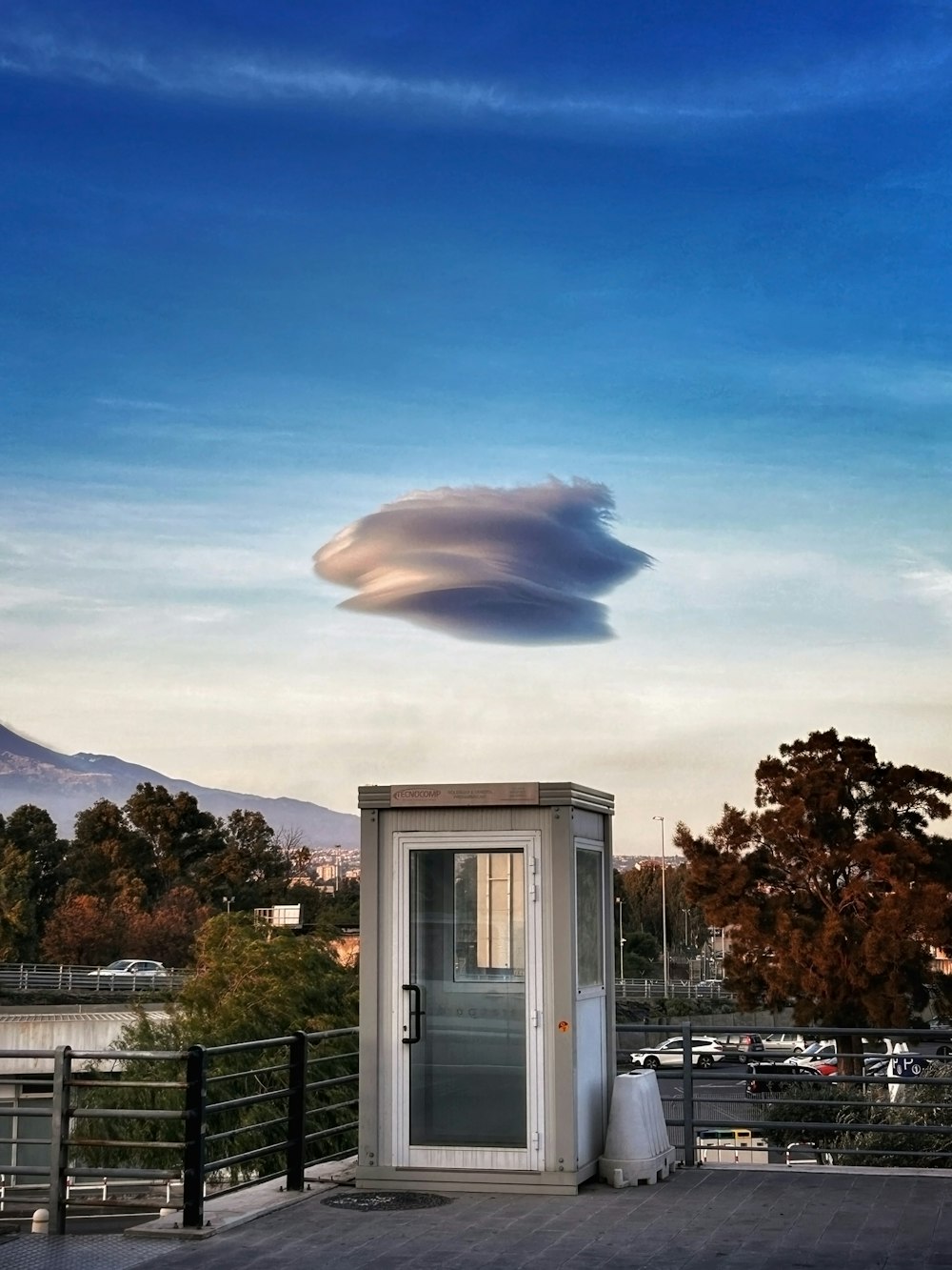 a small outhouse with a large cloud in the sky