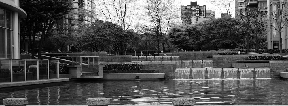 a black and white photo of a pond in a city