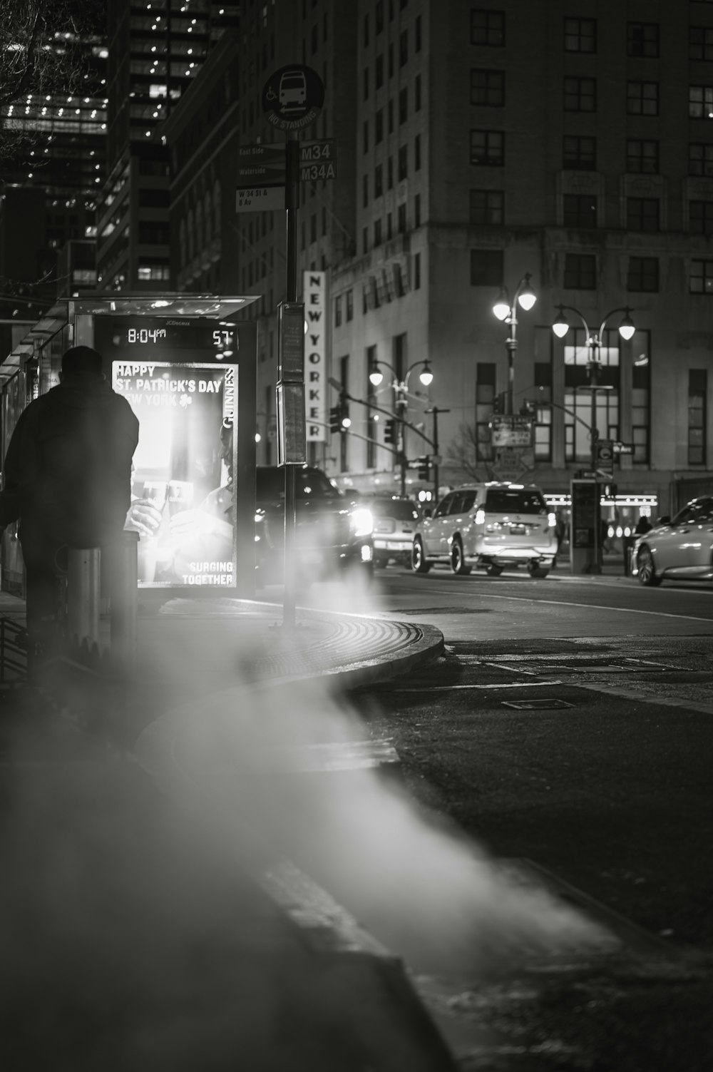 a black and white photo of a man standing on a street corner