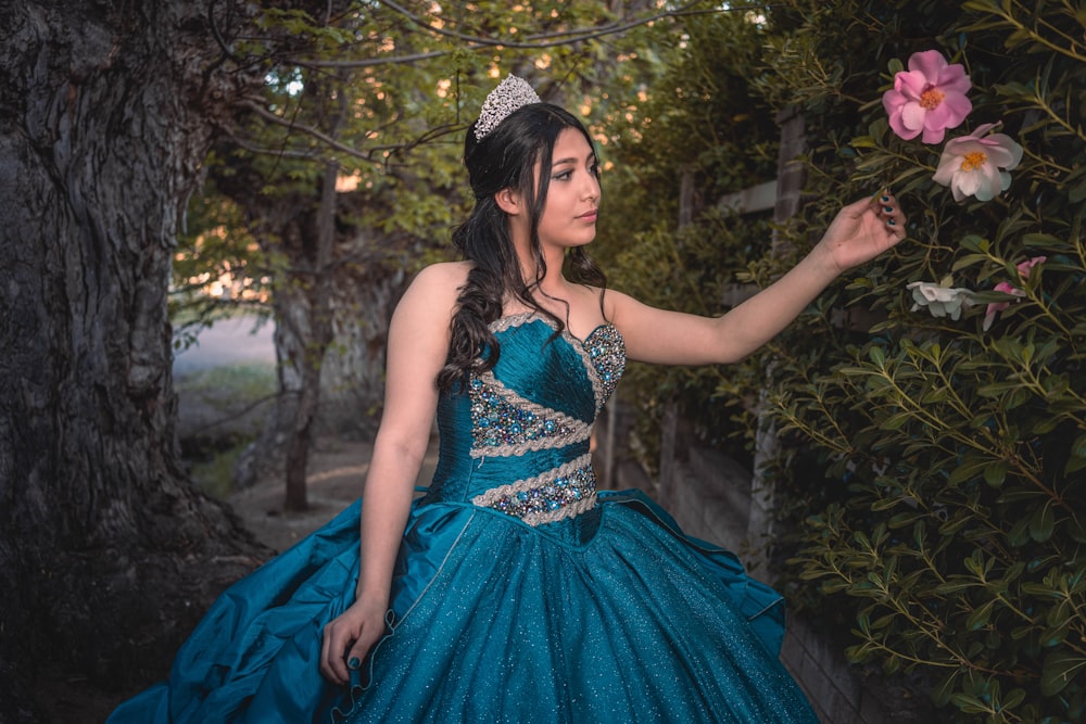 a woman in a blue dress holding a flower