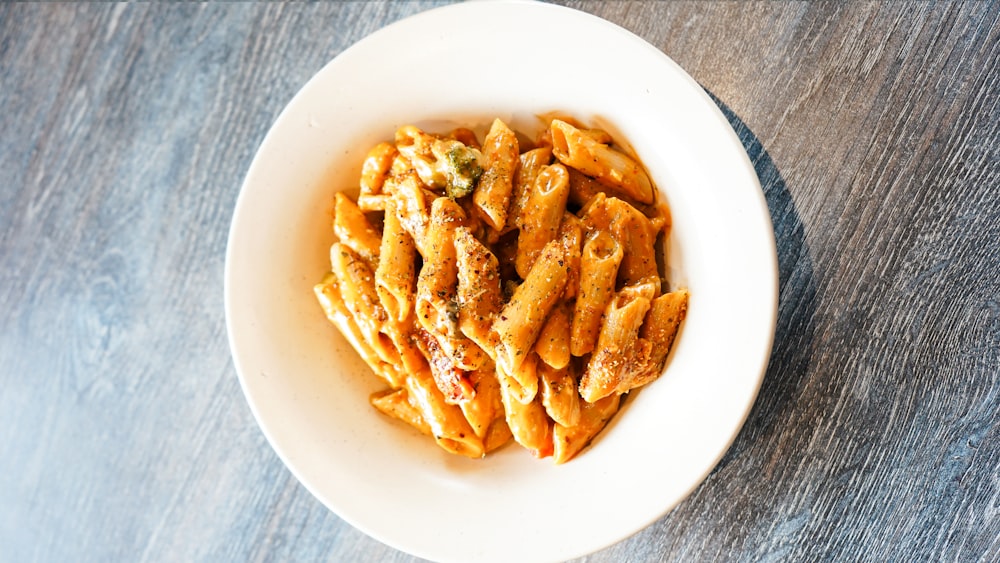 a white bowl filled with pasta on top of a wooden table