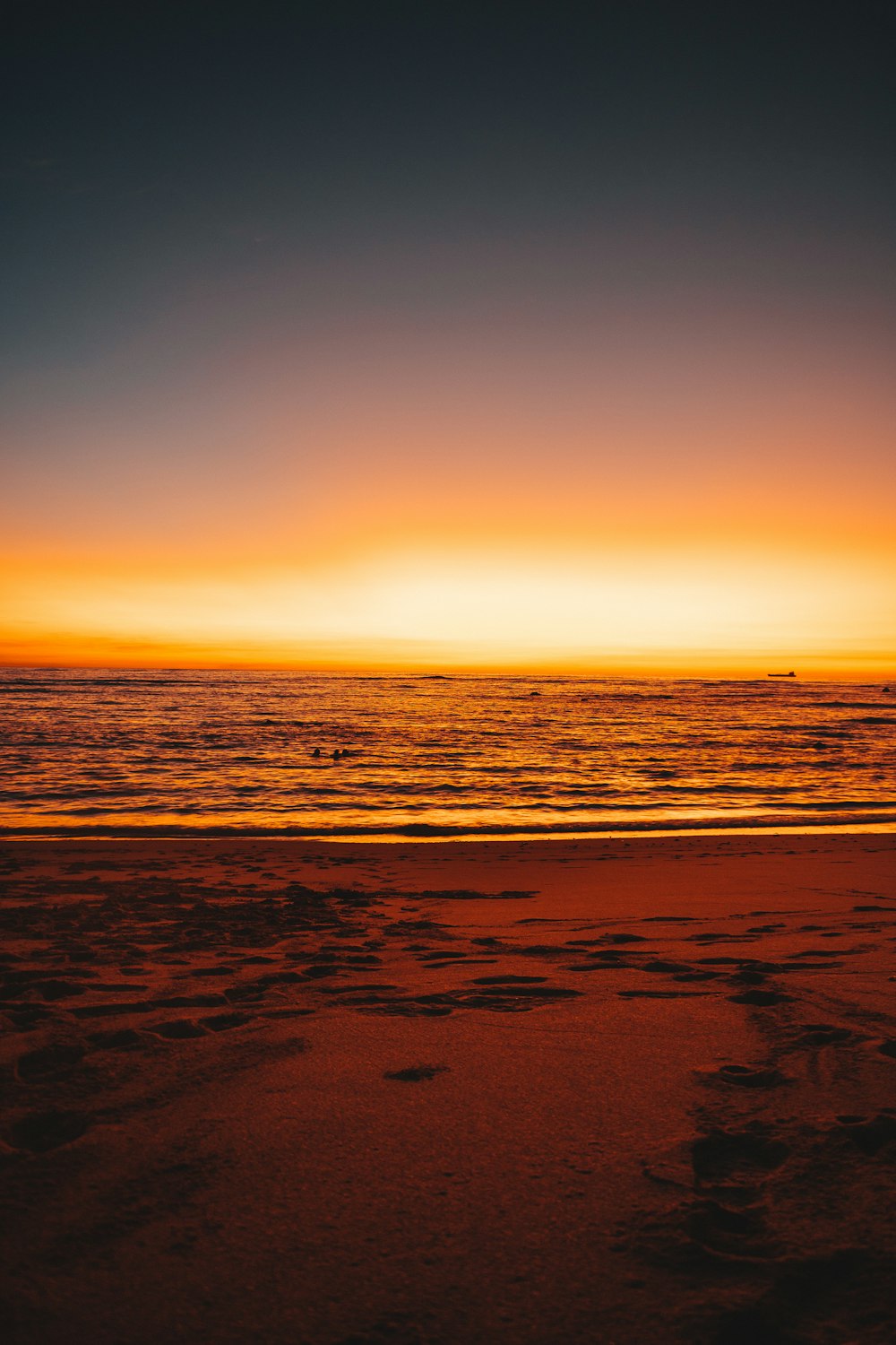 the sun is setting over the ocean on the beach