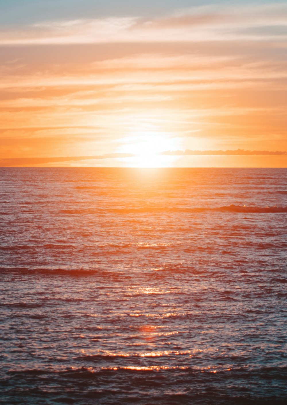 a large body of water with a sunset in the background