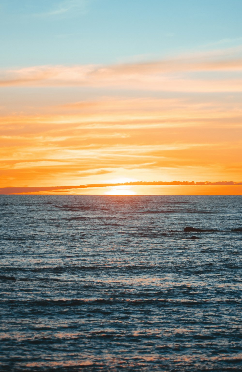 a large body of water with a sunset in the background