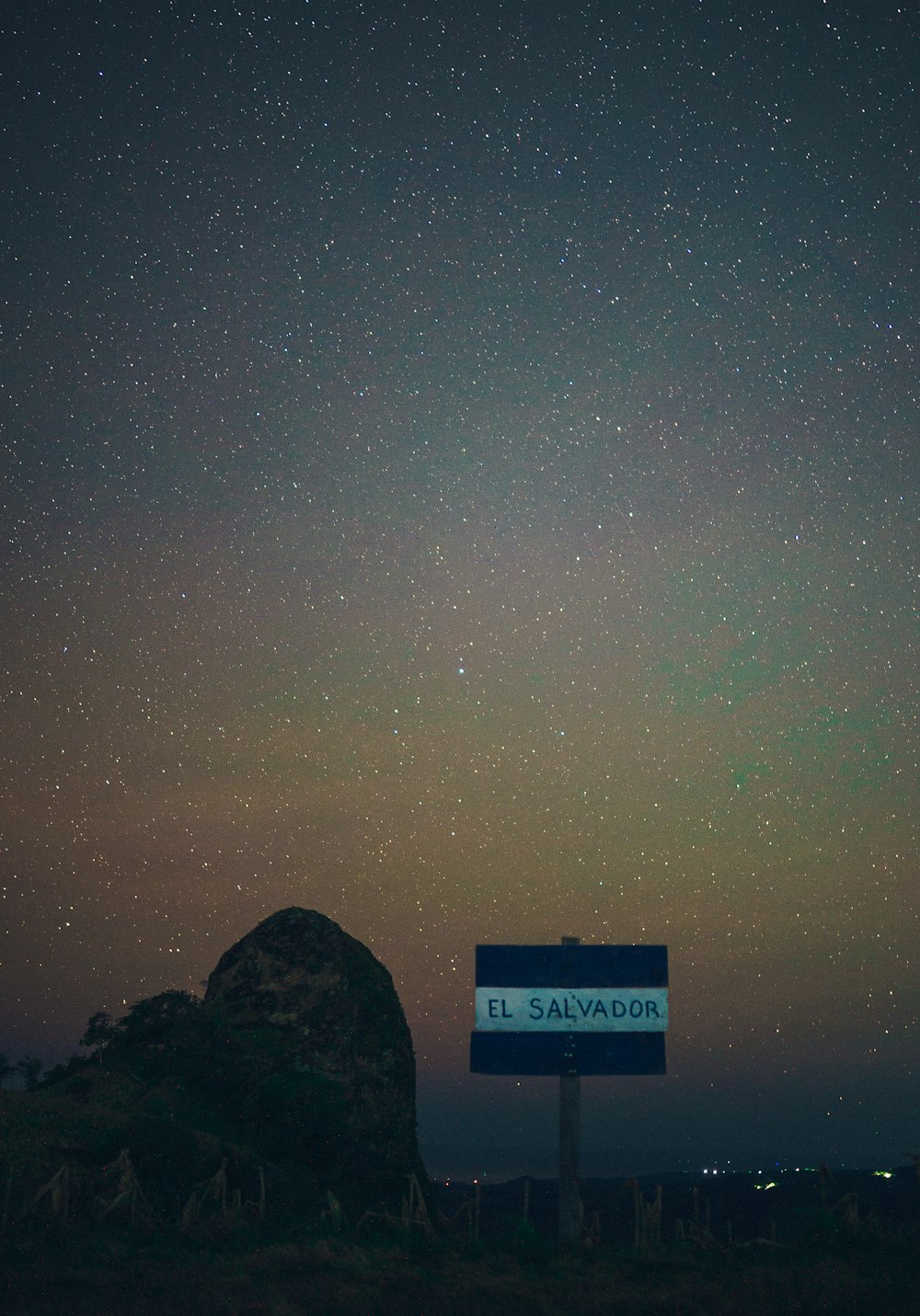 a street sign sitting under a night sky filled with stars