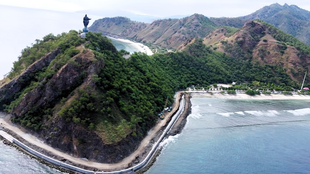 a man standing on top of a mountain next to the ocean