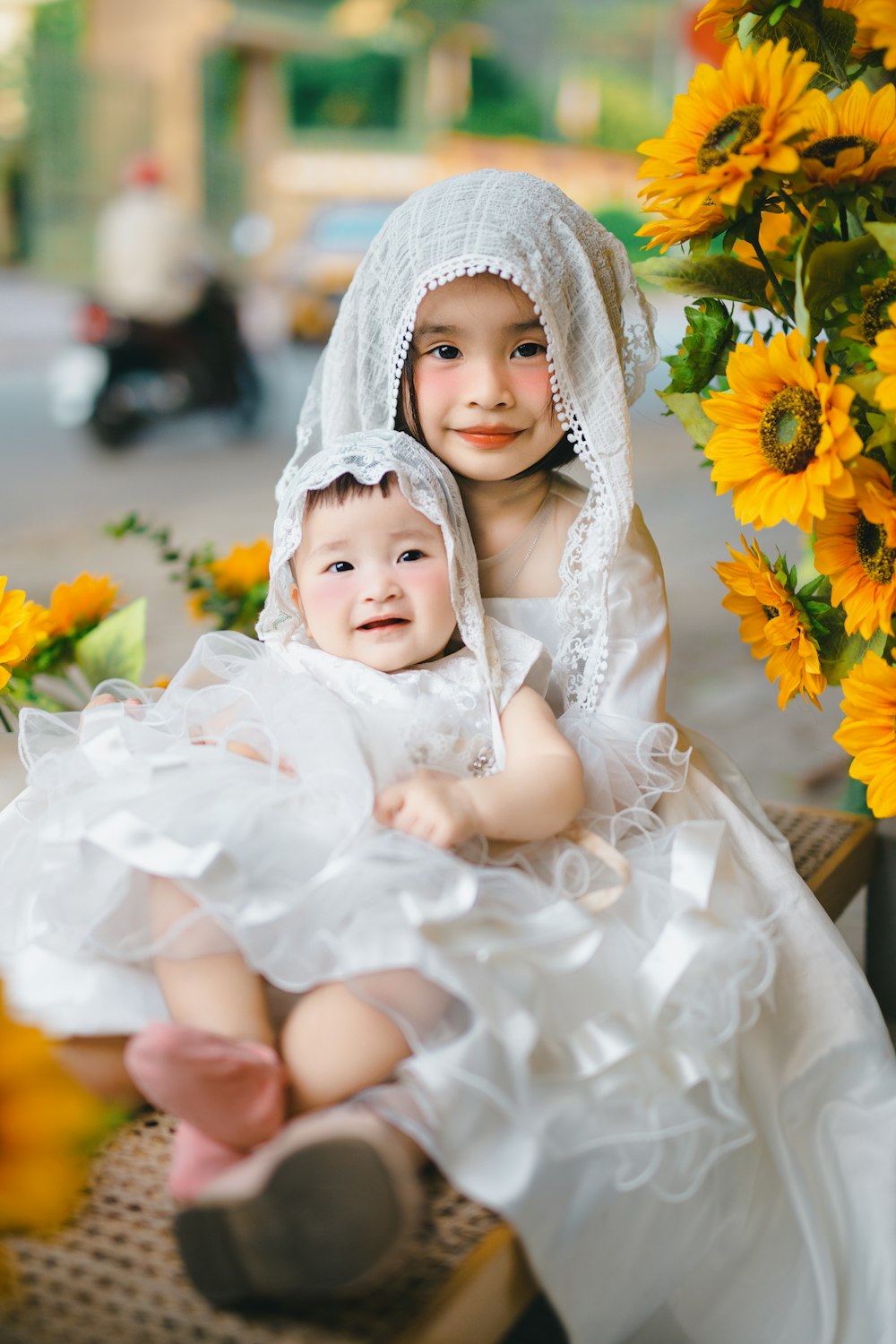 two young children dressed in white sitting next to each other