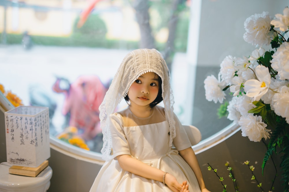 a little girl dressed in a white dress and veil