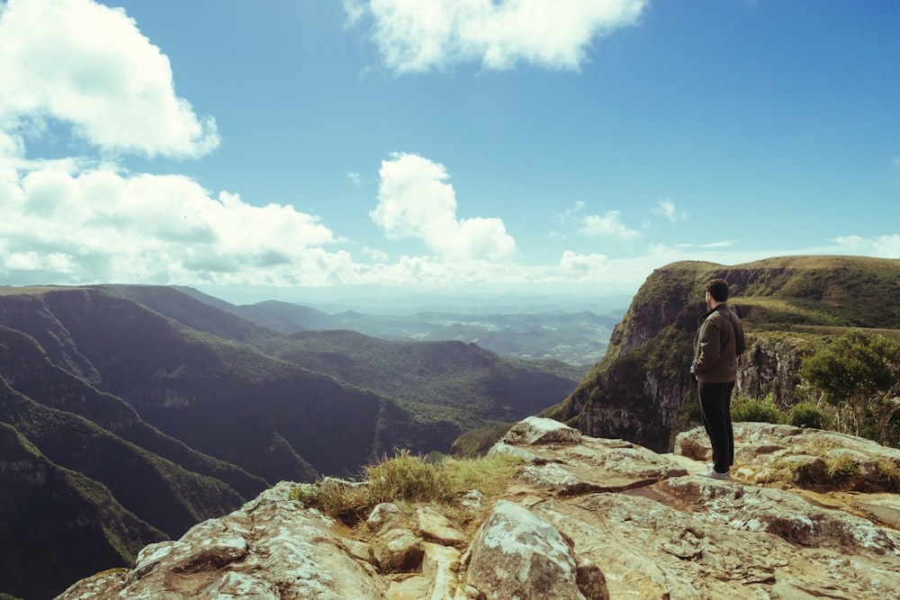 a man standing on top of a mountain overlooking a valley