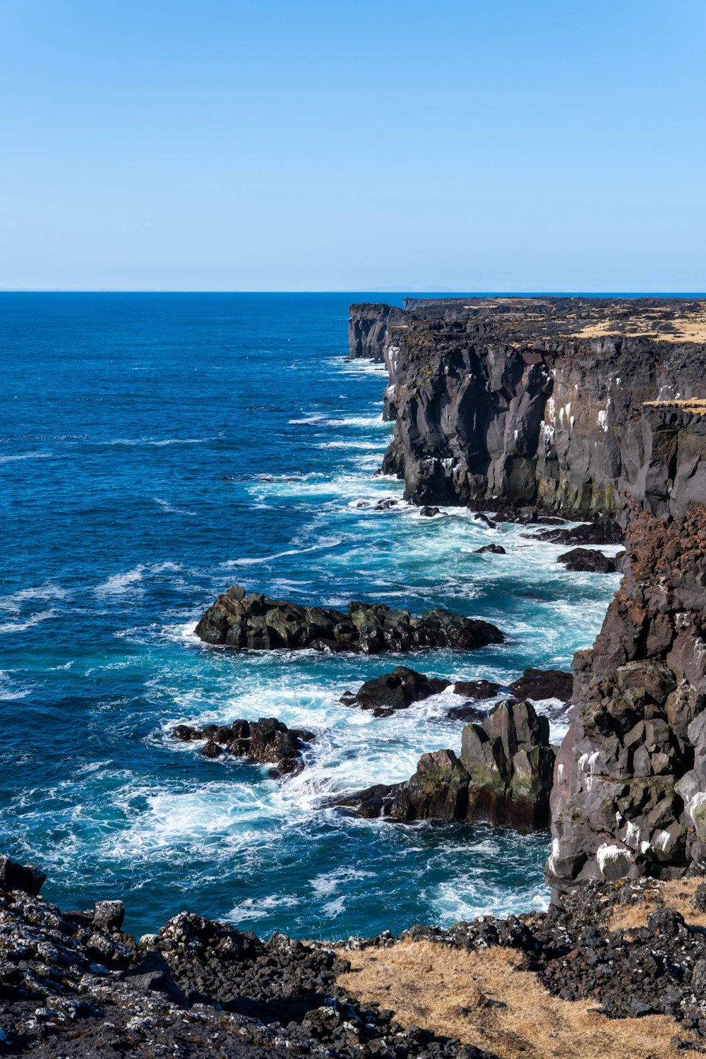 a rocky cliff overlooks the ocean on a clear day