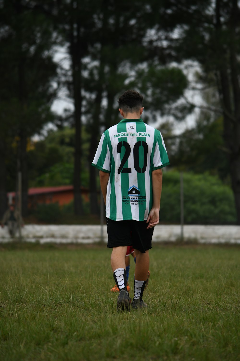a young boy in a green and white soccer uniform