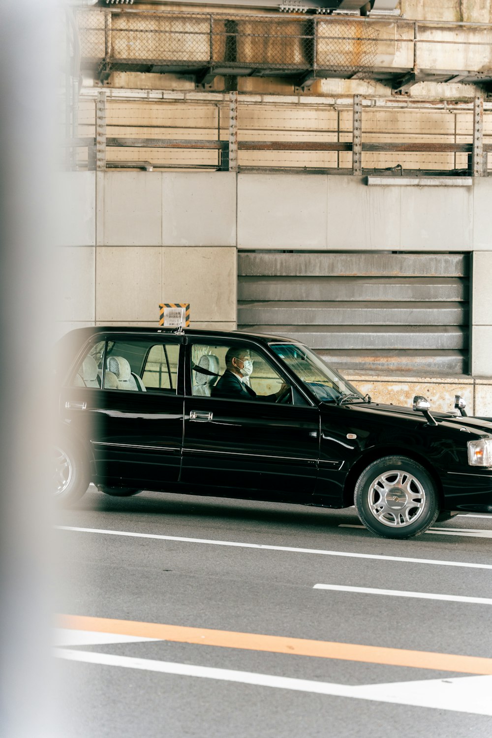 a black car driving down a street next to a tall building