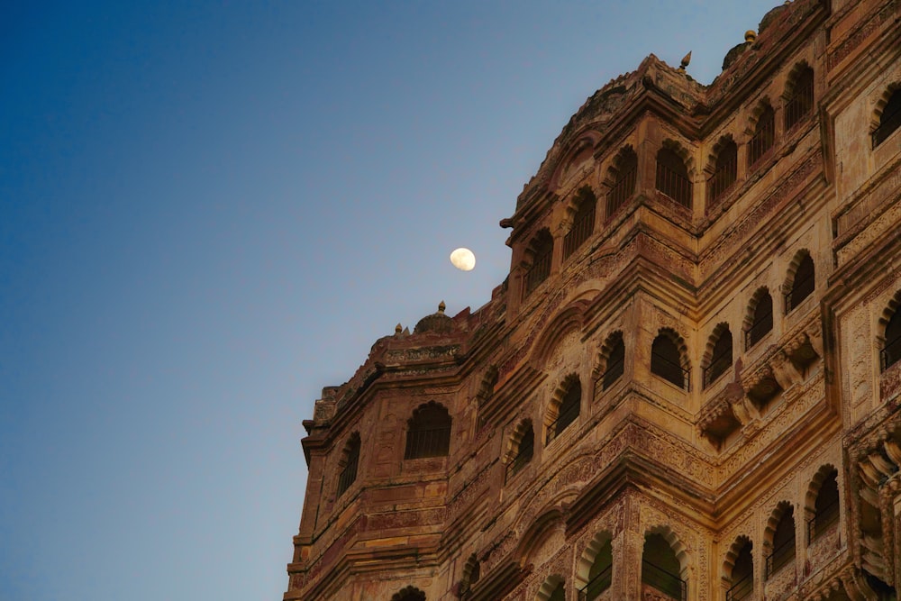 a full moon is seen in the sky above a building