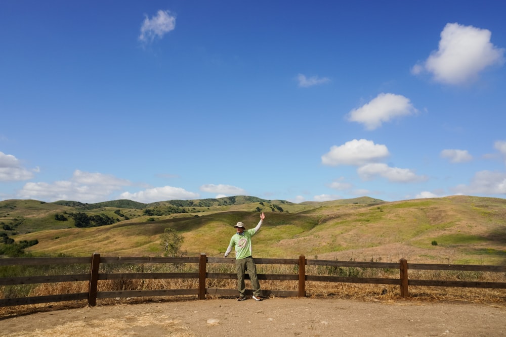 a man standing on top of a dirt field next to a fence