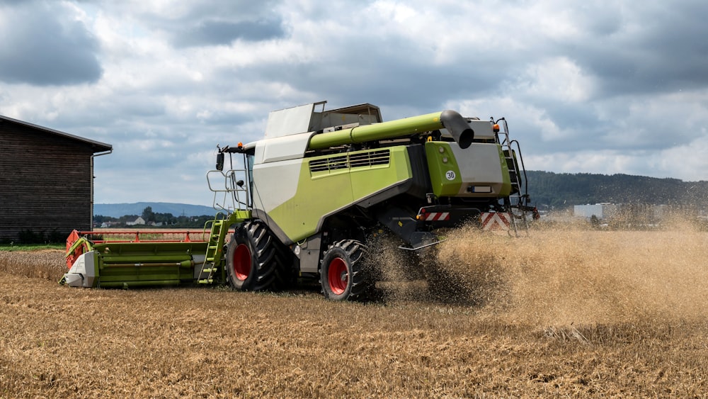 a green and white combine is driving through a field