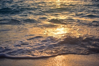 the sun is setting over the water at the beach