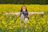 a woman standing in a field of yellow flowers