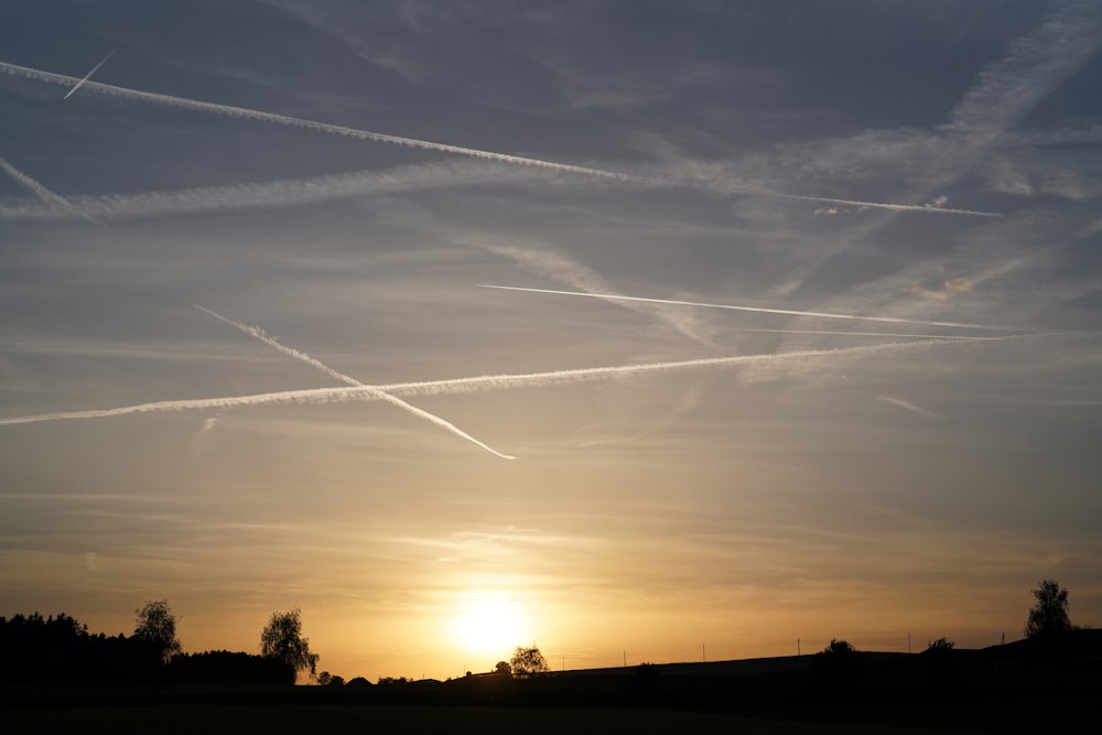 a sunset with contrails in the sky